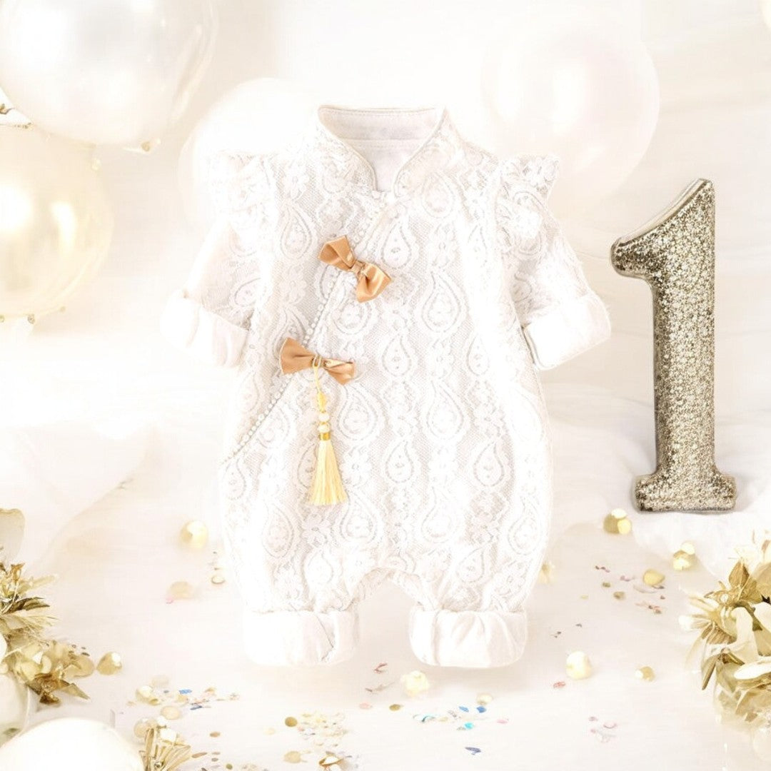 A white holiday baby girl romper with mandarin collar and frog button closures, featuring cute lace details and festive gold accents by Ashberryco. A perfect baby girl's special occasion outfit for Chinese New Year, baby 100 days celebrations, first birthday parties, and flower girls dress for Chinese weddings and traditional tea ceremonies!